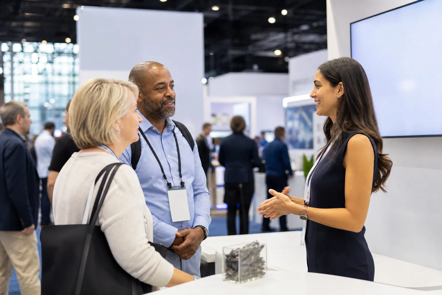 Un exposant discute avec deux visiteurs sur un stand de salon professionnel