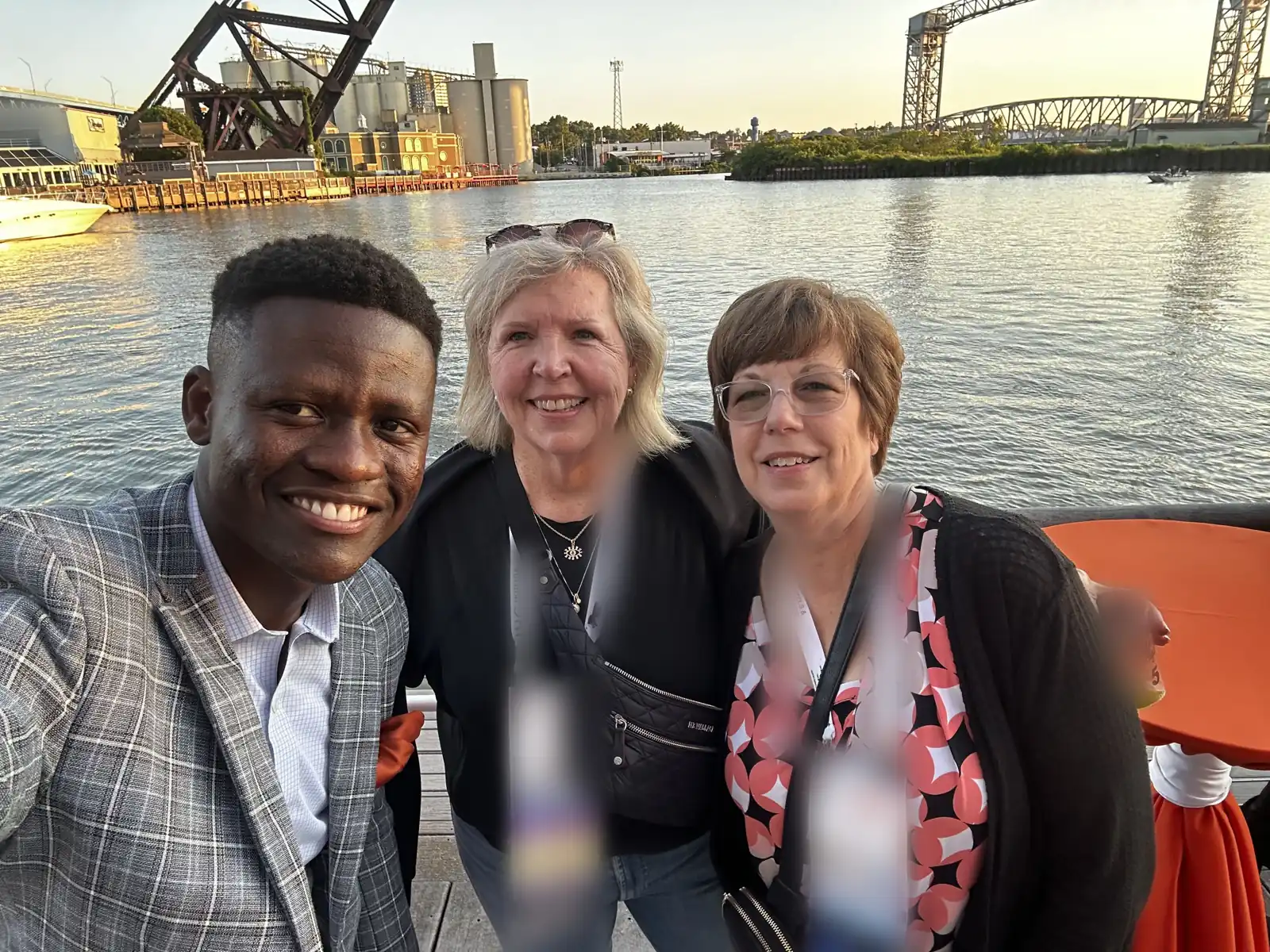 Three members smiling at a riverside evening reception